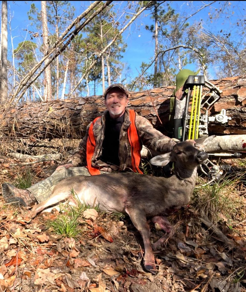 Hunter in blaze orange with a recovered doe and bow