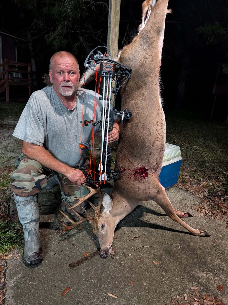 Hunter with a whitetail taken at night, white arrows in the bow-mounted quiver